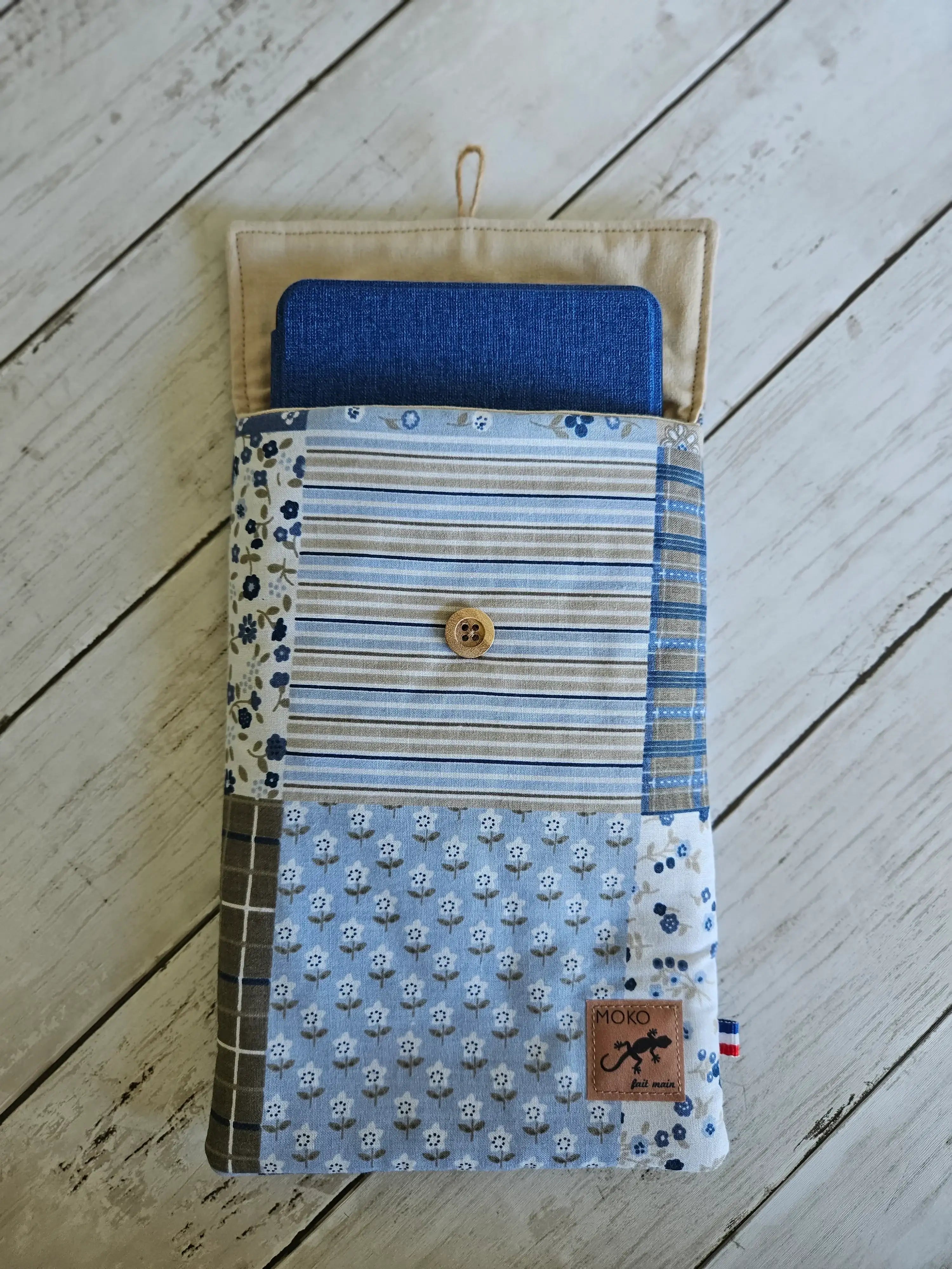 Pochette tissu matelassée bleu motifs fleurs et rayures avec bouton, sur fond bois blanc