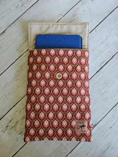 Pochette tissu motif rose avec bouton en bois, contenant une tablette bleue, sur fond bois.