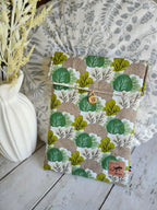 Pochette tissu motif feuilles vertes et marron, bouton en bois, accessoire mode sur fond naturel