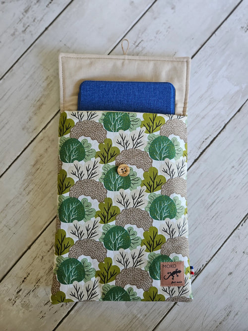 Pochette tablette motif feuillage vert et beige, bouton bois, sur fond bois clair.