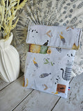 Pochette tissu motifs chats et poissons, accessoires mode, posée sur table en bois, déco florale.
