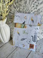 Pochette tissu motifs chats et poissons, accessoires mode, posée sur table en bois, déco florale.
