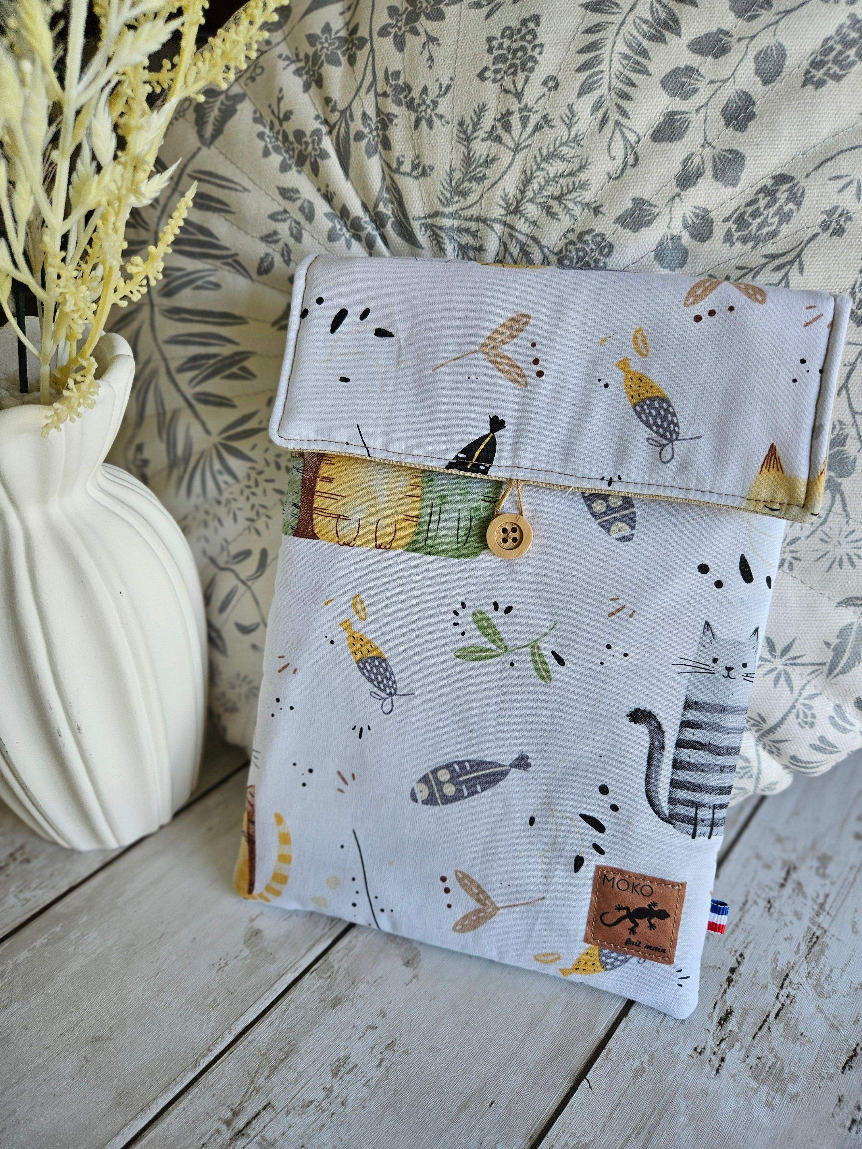 Pochette tissu motifs chats et poissons, accessoires mode, posée sur table en bois, déco florale.