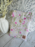 Housse à livre liseuse en tissu fleuri pastel avec bouton en bois, décor champêtre.