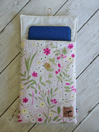 Housse de livre liseuse motif fleuri pastel, bouton bois, sur fond en bois blanc.