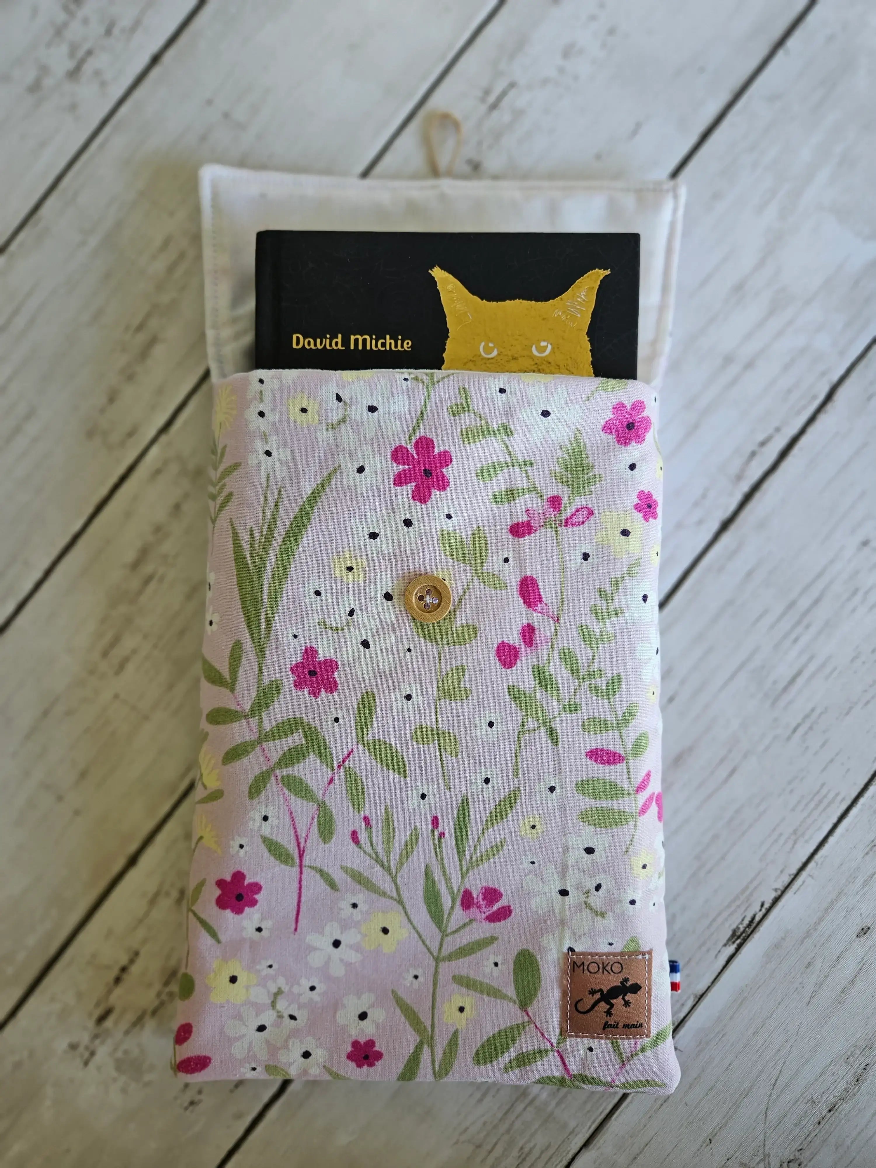 Housse à livre en tissu fleuri pastel avec bouton en bois, livre partiellement inséré