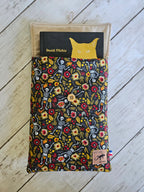 Housse à livre en tissu fleuri et motifs squelettes, bouton bois, sur fond en bois clair.