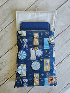 Étui tissu bleu à motifs plage, pour tablette, sur fond bois blanc.