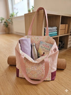 Sac à main en tissu floral rose avec serviette, gourde et livre de yoga, idéal pour le bien-être et la pratique en Vendée