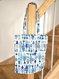 Totebag en tissu motif poissons bleus suspendu à une rambarde en bois, accessoire fait main.