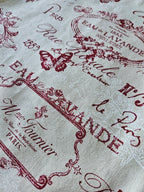Tissu beige imprimé écriture vintage, motifs papillon et fleurs rouges, style rétro français.