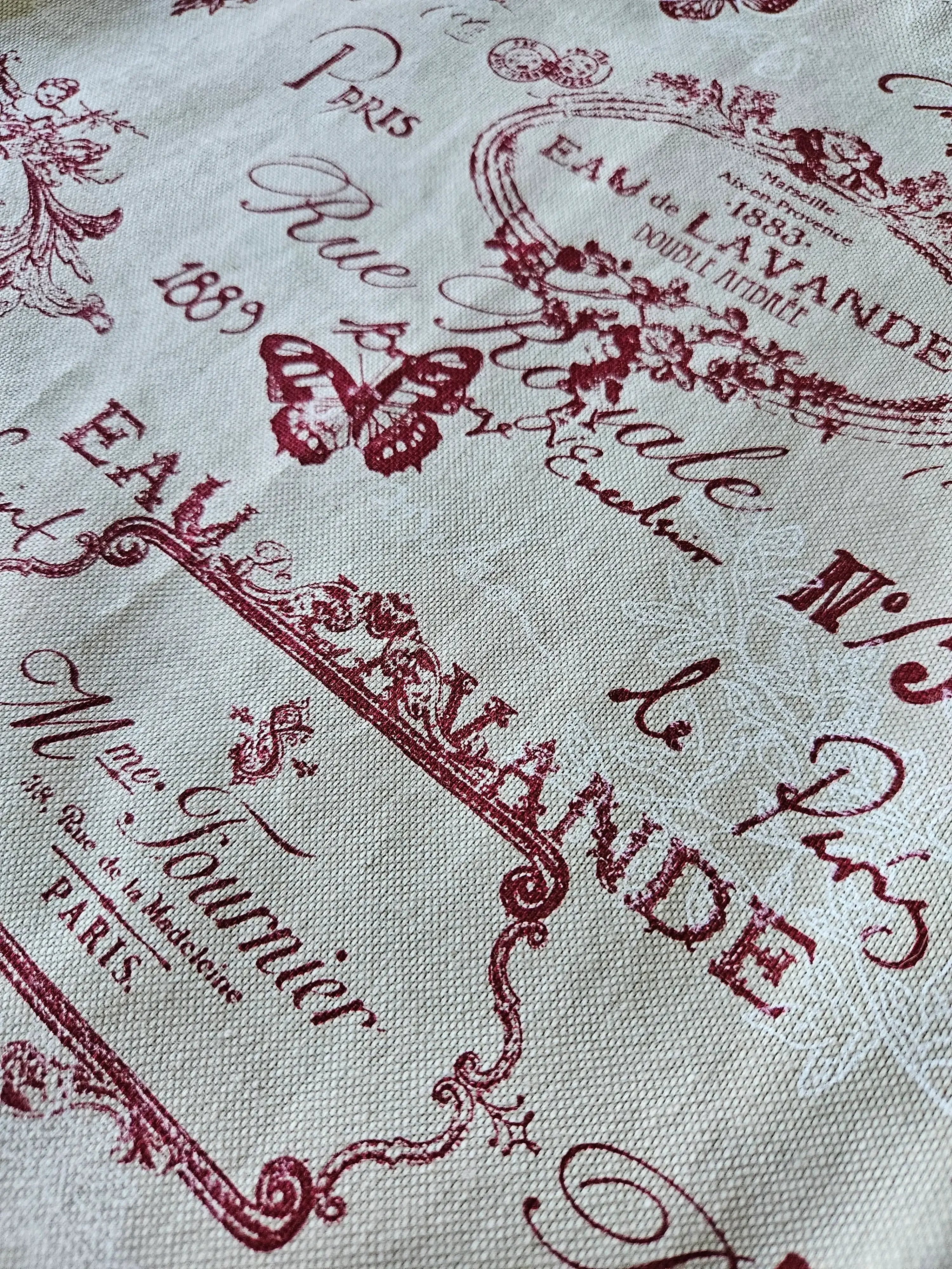 Tissu beige imprimé écriture vintage, motifs papillon et fleurs rouges, style rétro français.