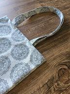 sac en tissu motif mandala noir sur fond blanc, posé sur table en bois