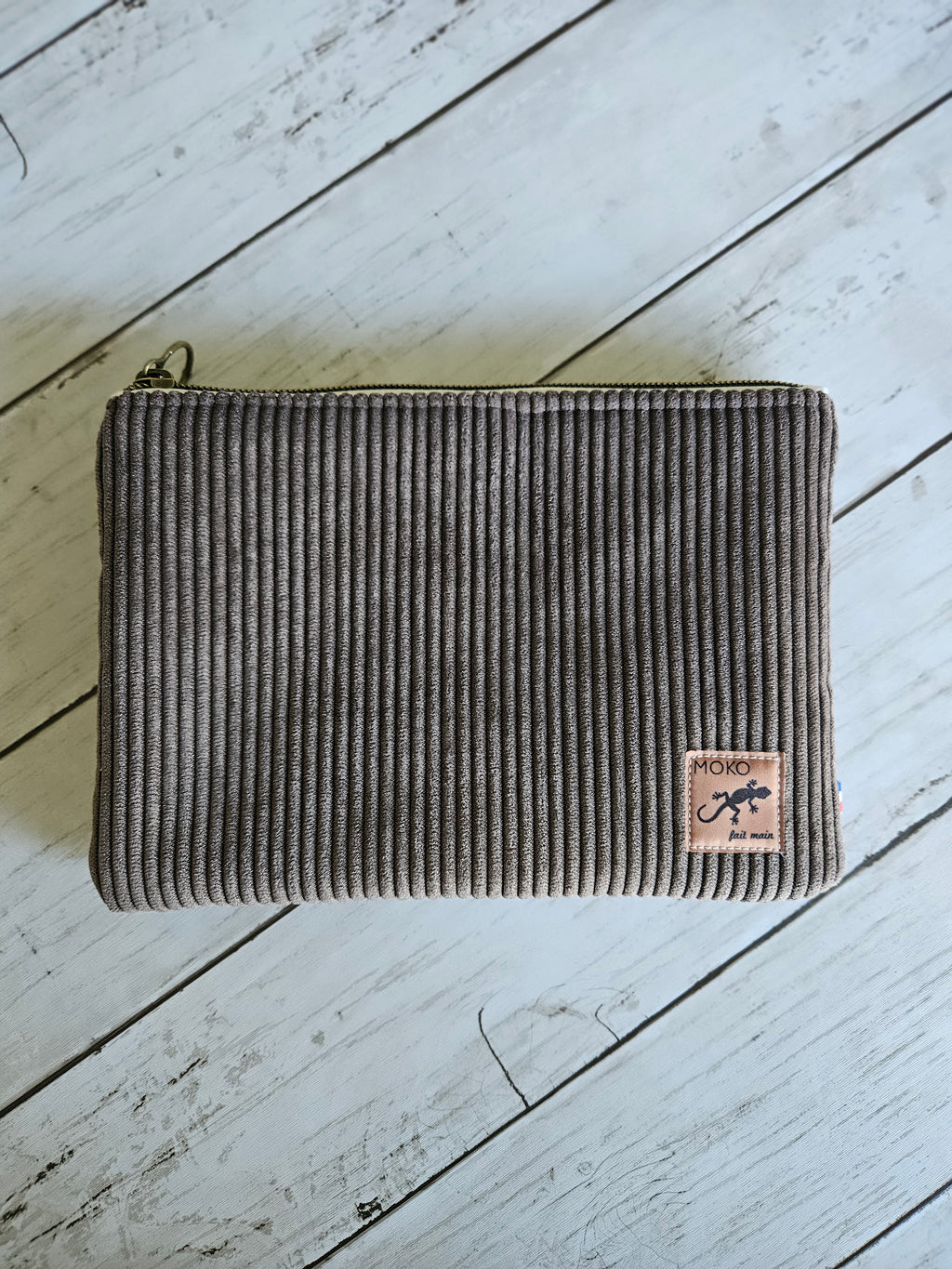 Trousse en velours marron à côtes, fermeture éclair, posée sur planche en bois clair