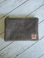 Trousse en velours marron à côtes, fermeture éclair, posée sur planche en bois clair