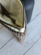 Trousse en velours marron à zip doré, vue de dessus sur fond bois clair