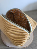 Trousse de toilette en velours côtelé jaune moutarde avec doublure à motif fleuri.