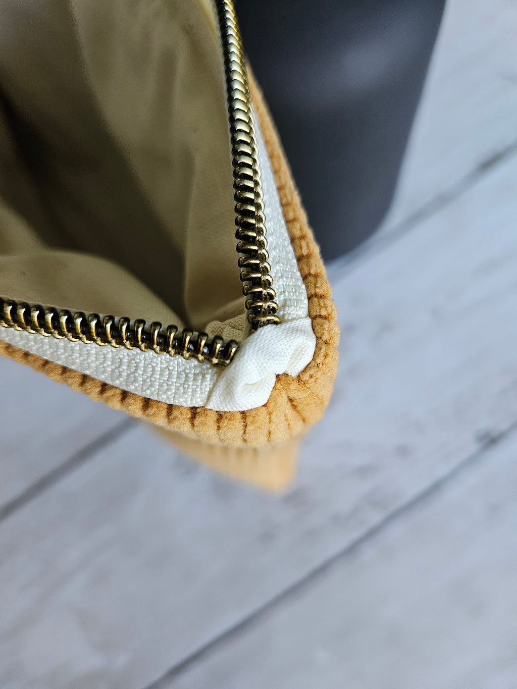 Trousse plate en velours jaune moutarde avec fermeture éclair dorée, vue en gros plan
