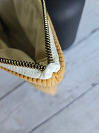 Trousse plate en velours jaune moutarde avec fermeture éclair dorée, vue en gros plan