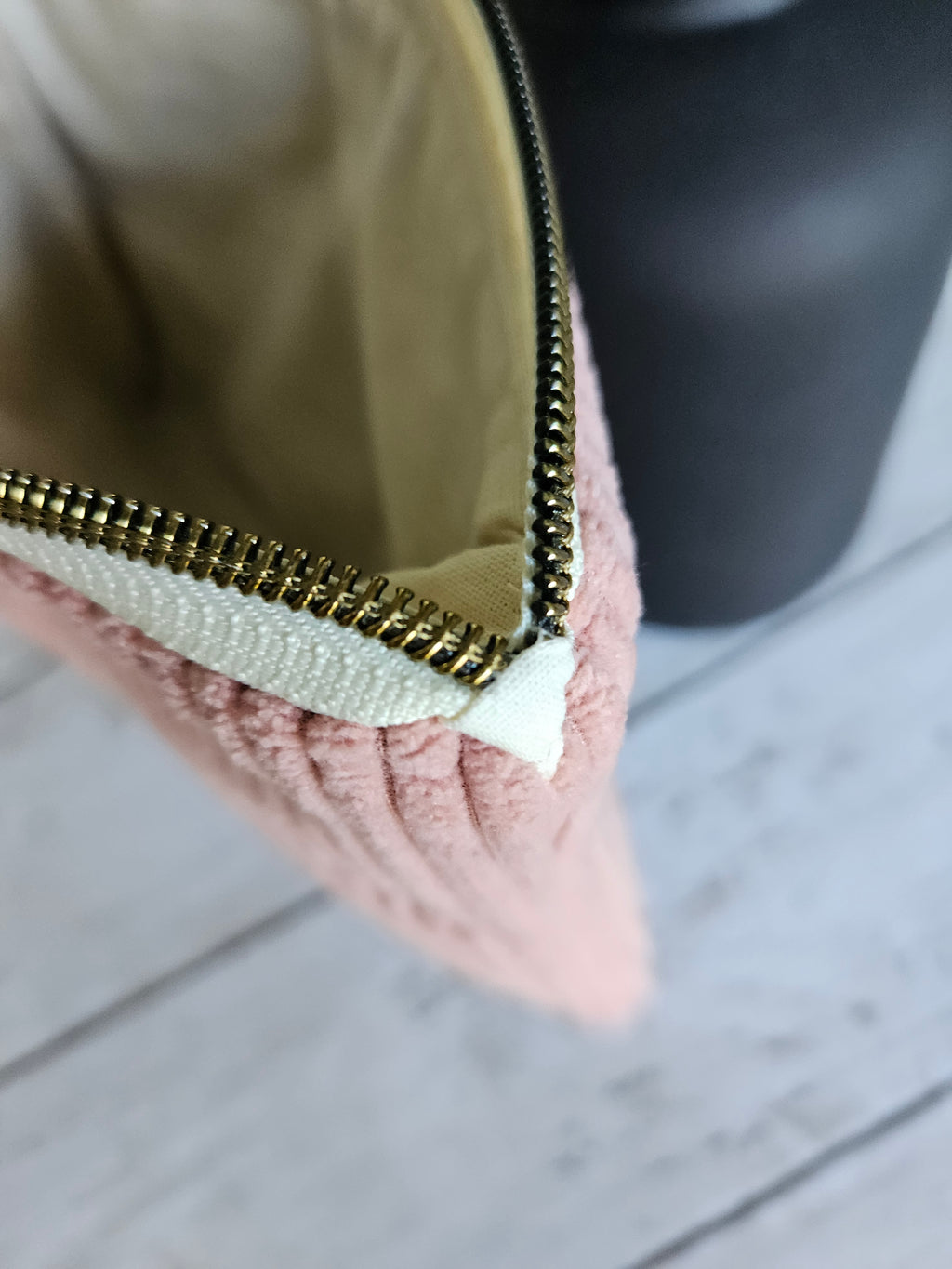 Trousse plate en velours rose avec fermeture éclair dorée, vue en gros plan sur intérieur beige