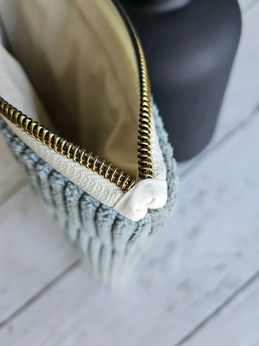 Trousse plate en velours vert d’eau avec fermeture éclair dorée, vue rapprochée