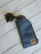 Étui à lunettes côtelé bleu avec lunettes de soleil, accessoire mode sur fond bois blanc