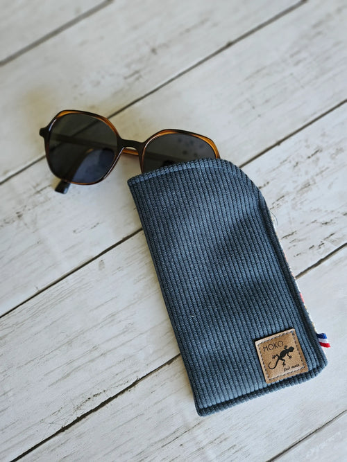 Étui à lunettes côtelé bleu avec lunettes de soleil, accessoire mode sur fond bois blanc