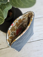 Petite pochette tissu bleu intérieur fleuri, accessoire mode sur fond bois clair.