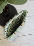 Pochette en tissu à motif floral jaune et bleu sur fond blanc, accessoire mode.