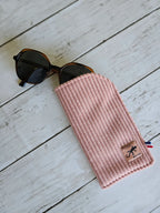 Étui à lunettes rose en tissu côtelé avec lunettes de soleil sur fond en bois, accessoire mode