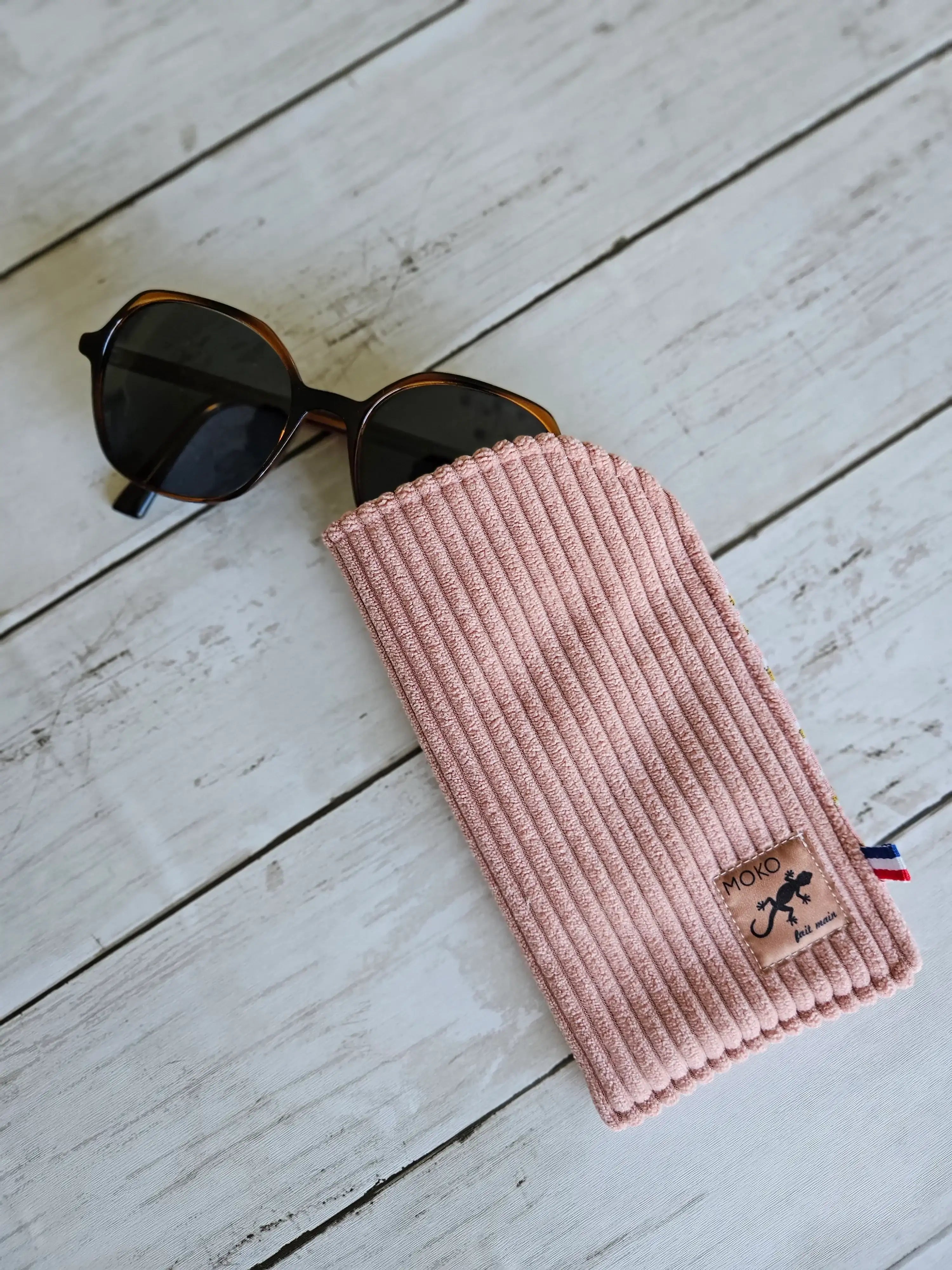 Étui à lunettes rose en tissu côtelé avec lunettes de soleil sur fond en bois, accessoire mode