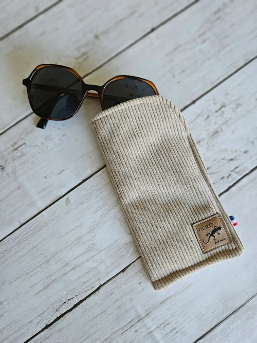 Étui en tissu beige pour lunettes de soleil, accessoire mode posé sur fond bois clair