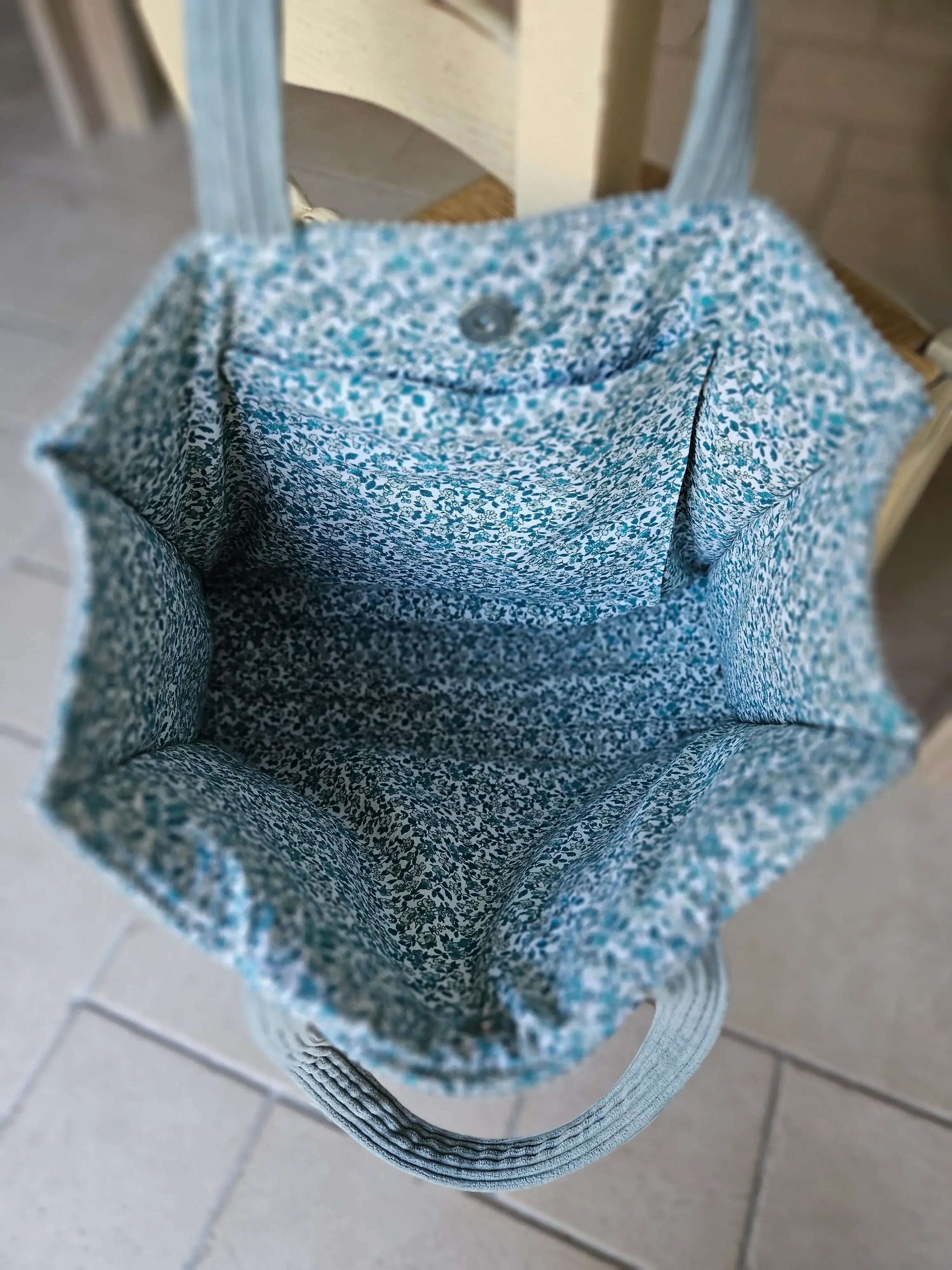 Intérieur d’un sac cabas en tissu bleu à motif fleuri, vue de dessus, accessoire mode tendance