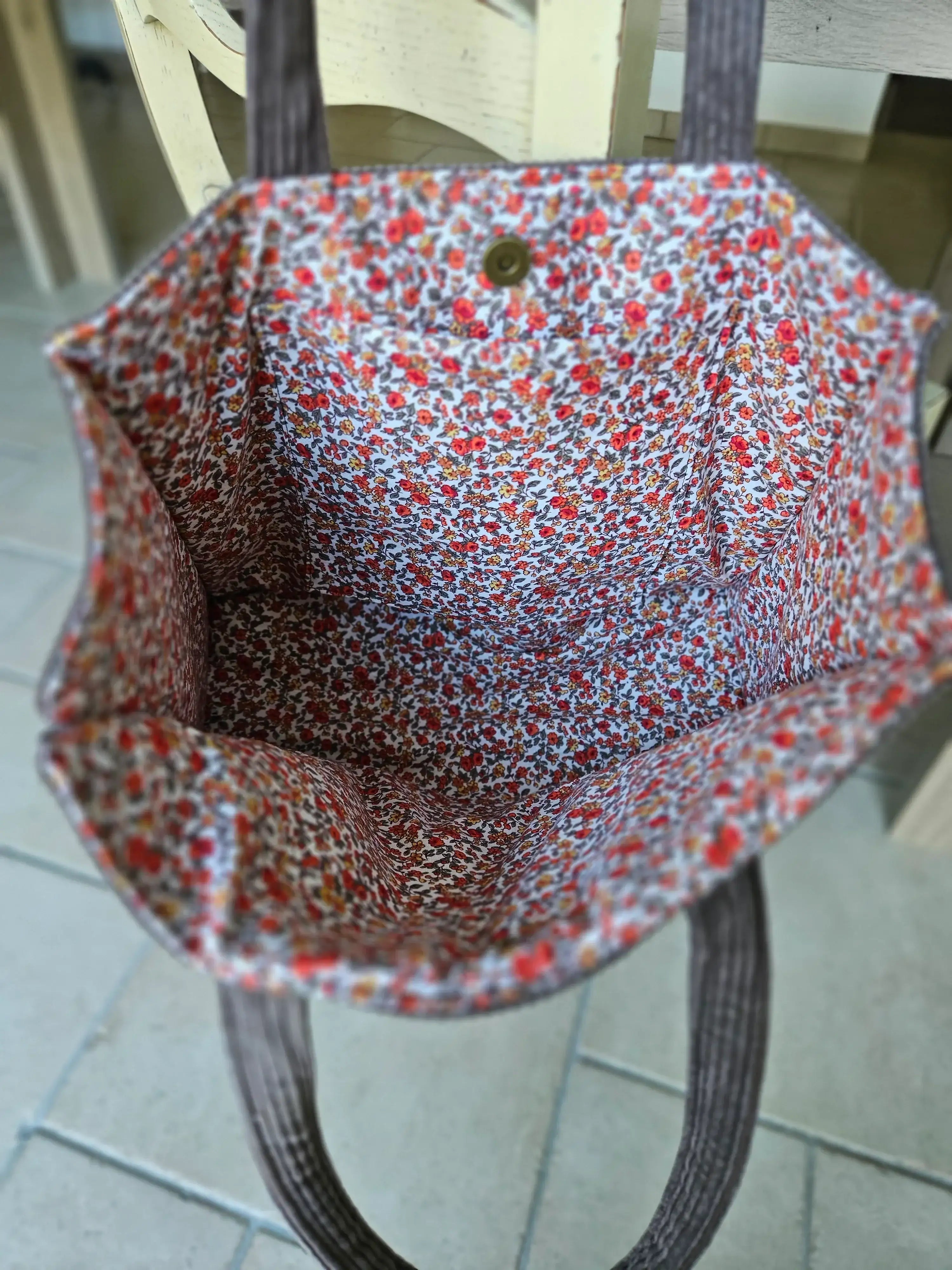 Intérieur d’un sac cabas avec doublure à fleurs rouges, bouton pression visible.