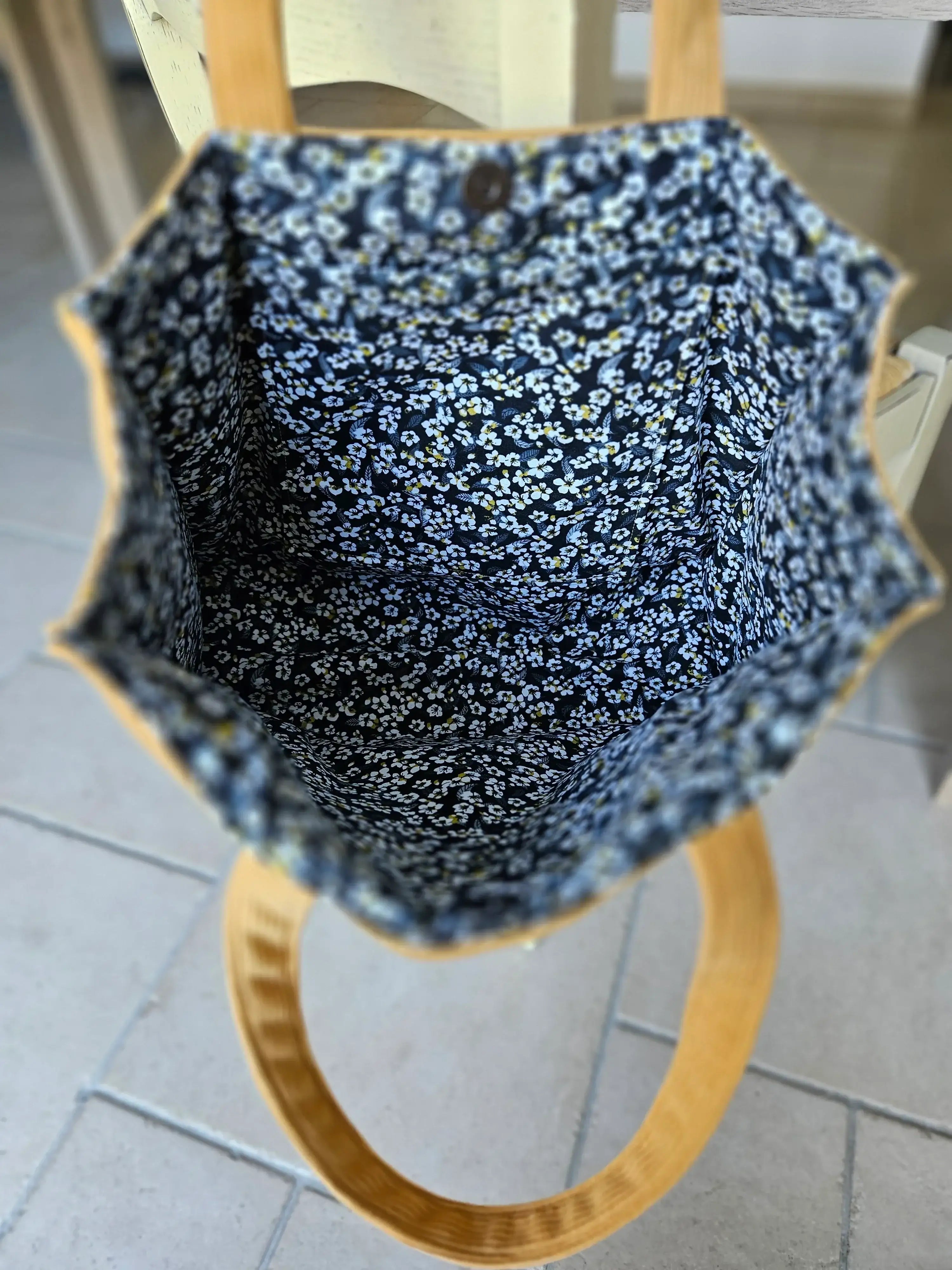 Intérieur d’un sac à main avec doublure tissu fleuri bleu et poignée ronde bois