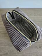 Pochette en velours côtelé beige avec fermeture éclair dorée et doublure à carreaux