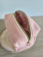 Trousse en velours rose à fermeture éclair dorée, doublure intérieure à motif fleuri.