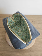 Pochette en velours bleu avec intérieur à motif floral, accessoire mode tendance.