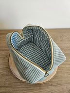 Pochette en velours côtelé vert ouverte, doublure intérieure à carreaux, posée sur bois