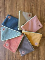 Ensemble de pochettes en velours côtelé colorées, accessoires mode tendance sur fond bois.