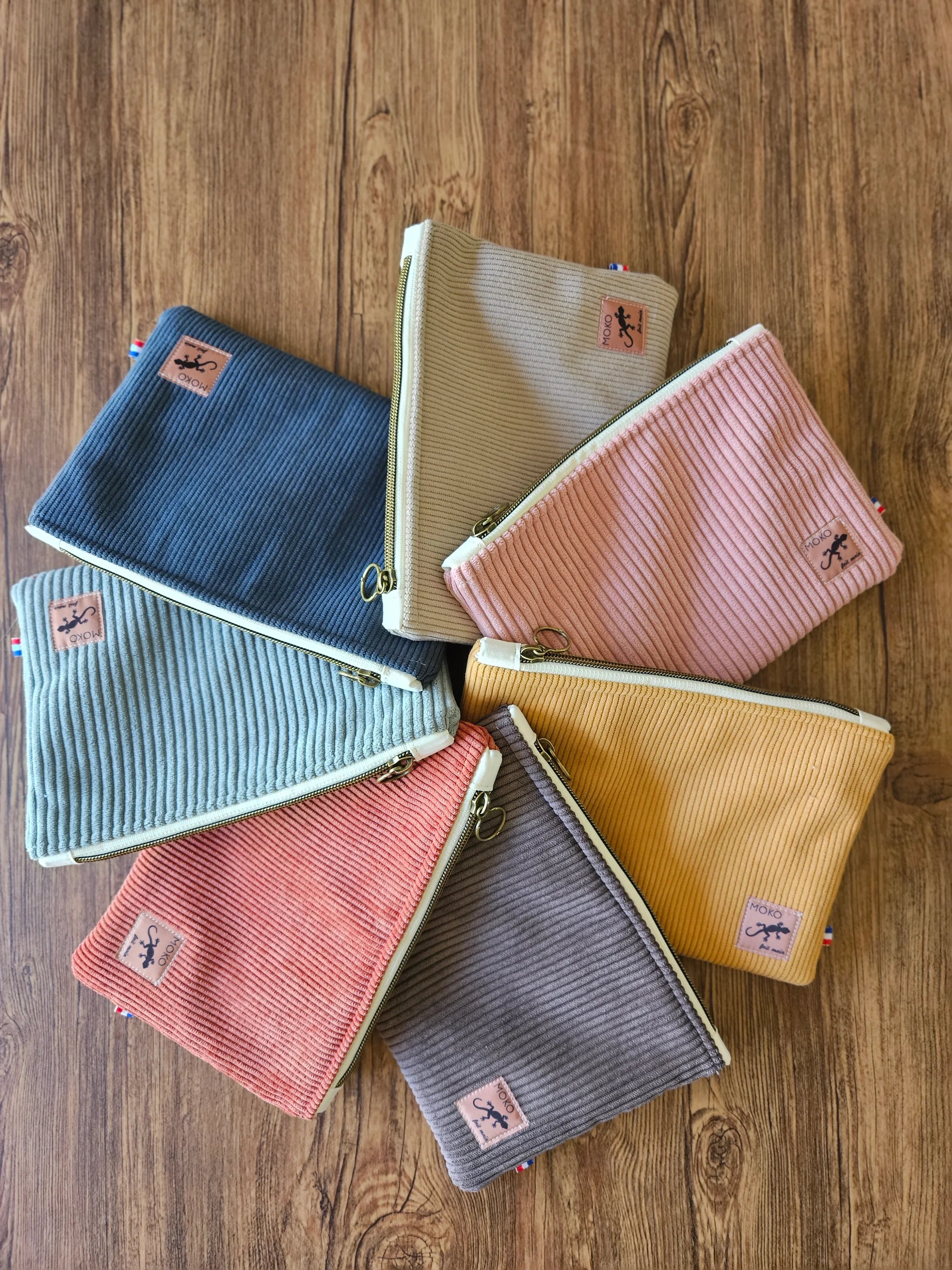 Ensemble de pochettes en velours côtelé colorées, accessoires mode tendance sur fond bois.